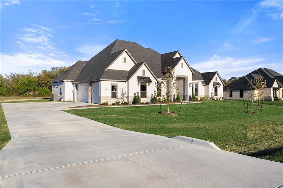 French provincial home featuring a garage and a front yard