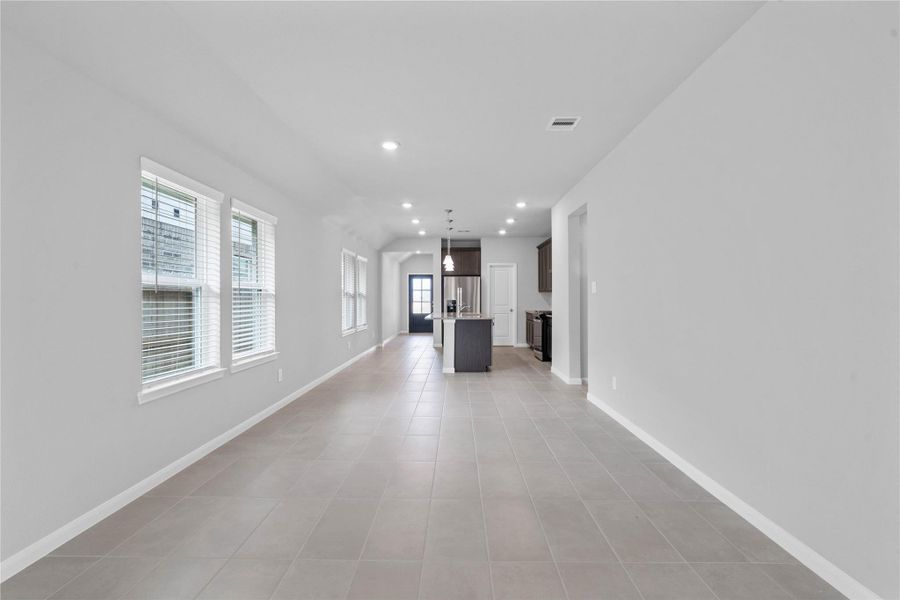 Enjoy meals in this sun-drenched space, featuring durable tile flooring, abundant natural light from the large windows (fitted with blinds), and recessed lighting.