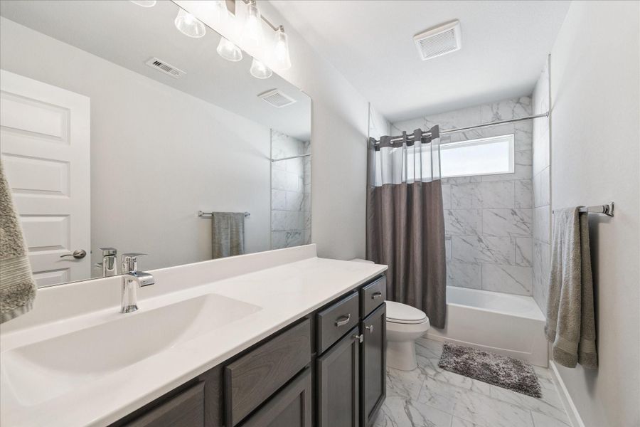 Elegant bathroom with a single sink vanity, marble walls in the bathtub area, and a high window providing natural light. Elegant bathroom with a single sink vanity, marble walls in the bathtub area, and a high window providing natural light.