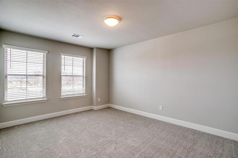 Unfurnished room featuring baseboards, visible vents, and light colored carpet