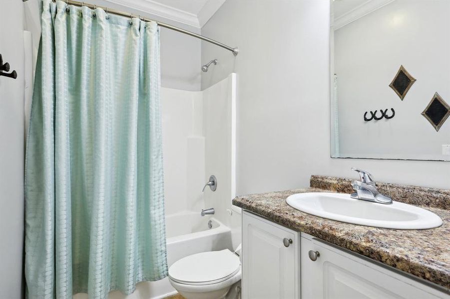 Full bathroom with vanity, ornamental molding, shower / bath combination with curtain, and toilet