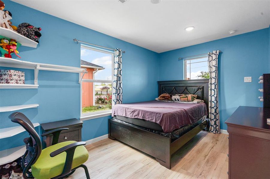 Bedroom featuring light wood-type flooring and multiple windows Bedroom featuring light wood-type flooring and multiple windows