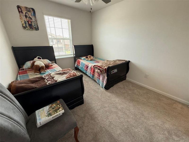 Bright room featuring a window with blinds, a ceiling fan, plush carpet, and white baseboards