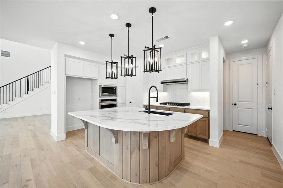 Kitchen with light wood-type flooring, white cabinetry, light stone countertops, and recessed lighting Kitchen with light wood-type flooring, white cabinetry, light stone countertops, and recessed lighting