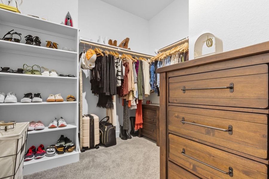 Primary closet with built in shelving and space for overhead storage.