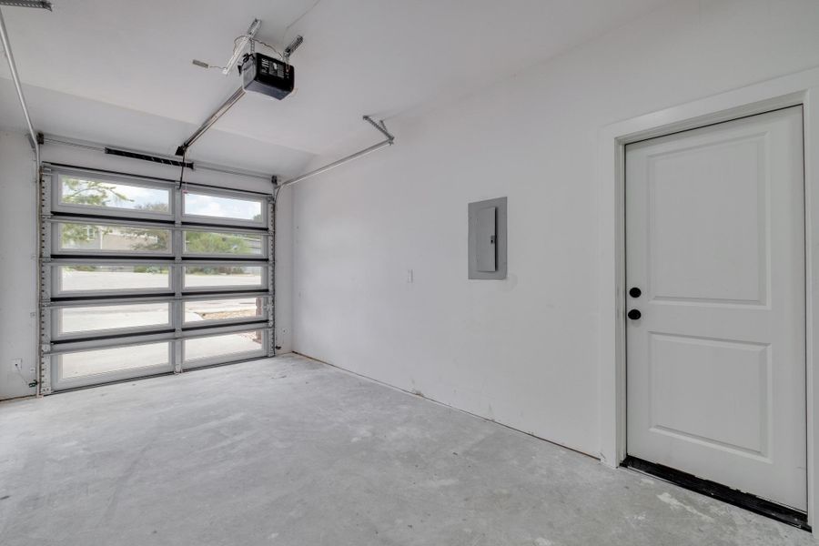 A well-lit garage features a modern glass panel door and clean concrete flooring. A well-lit garage features a modern glass panel door and clean concrete flooring.