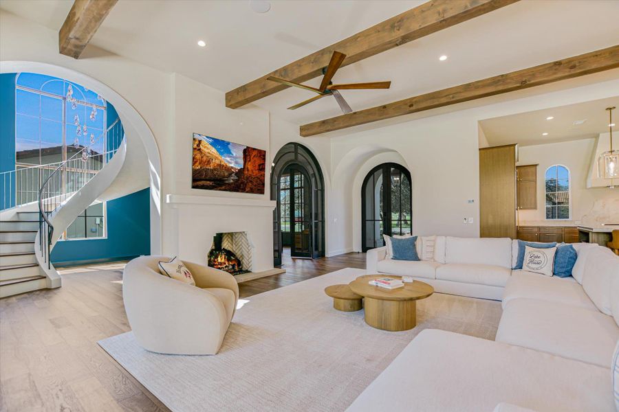 Living room featuring recessed lighting, beamed ceiling, light wood finished floors, a lit fireplace, and a ceiling fan