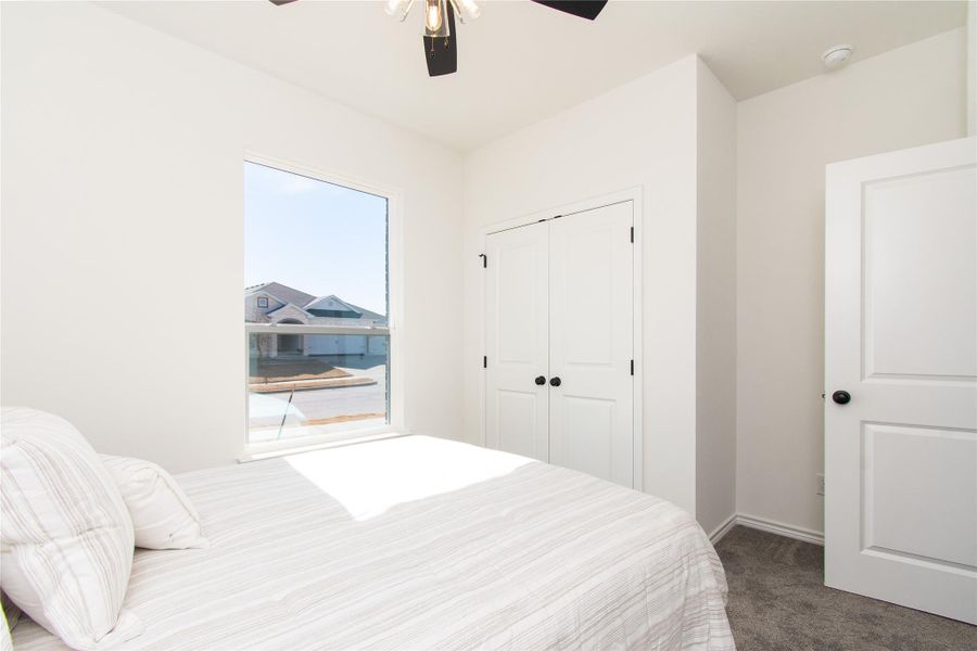 Carpeted bedroom with ceiling fan and a closet