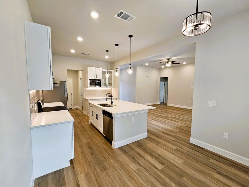 Kitchen featuring glass insert cabinets, recessed lighting, white cabinets, open floor plan, and backsplash