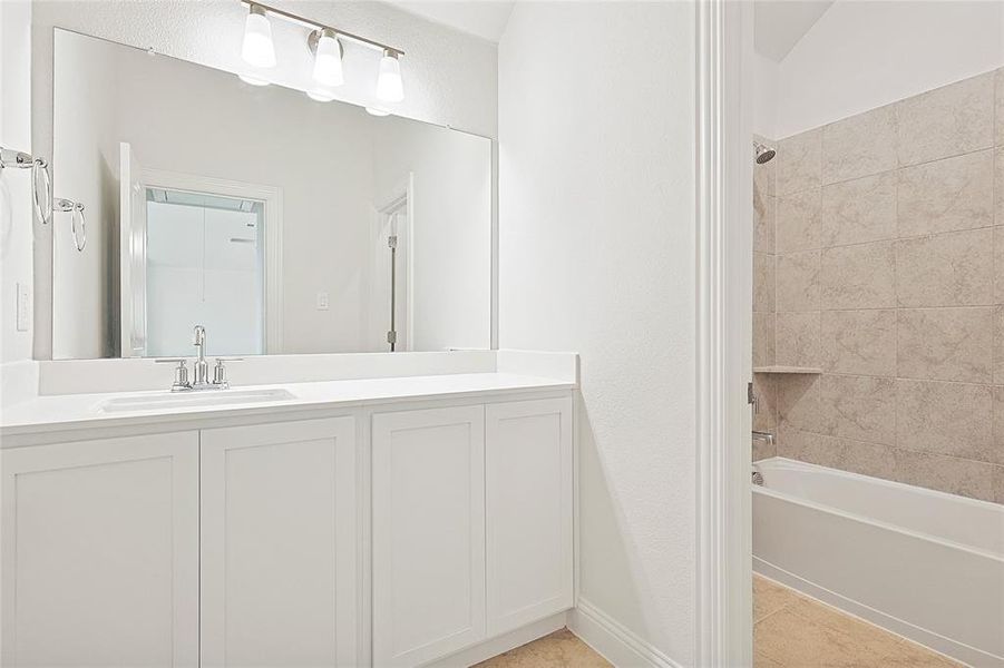 Bathroom featuring vanity, tiled shower / bath combo, and tile patterned floors