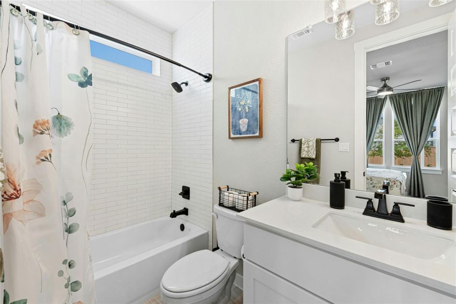 Ensuite bathroom featuring vanity, shower / tub combo with curtain, and a ceiling fan