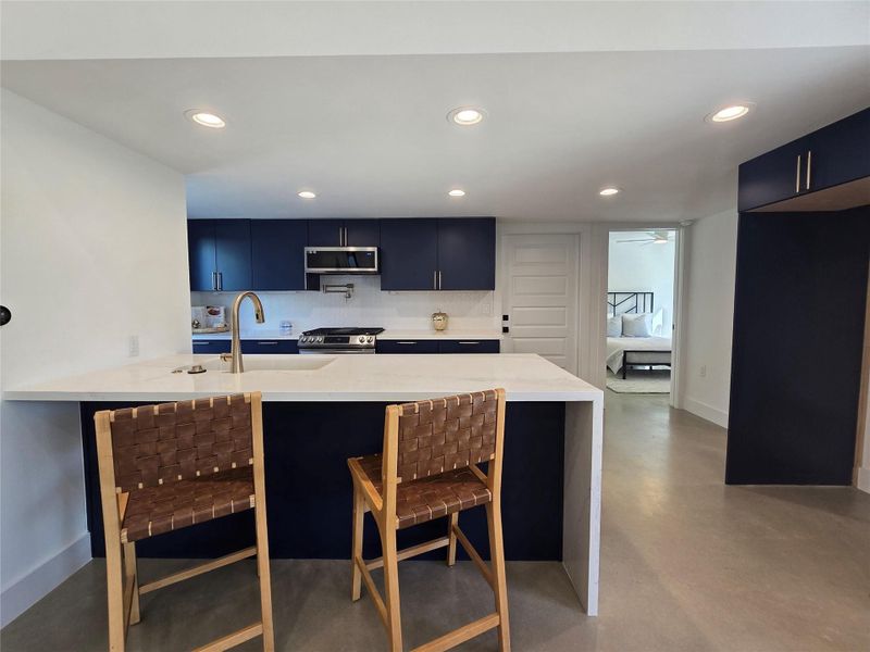 Kitchen peninsula with an overhang for quick bites and eating at it, with a desirable waterfall side upgrade on the thick Silestone counters. Refrigerator cabinet allows a full size 36" fridge. Kitchen peninsula with an overhang for quick bites and eating at it, with a desirable waterfall side upgrade on the thick Silestone counters. Refrigerator cabinet allows a full size 36" fridge.