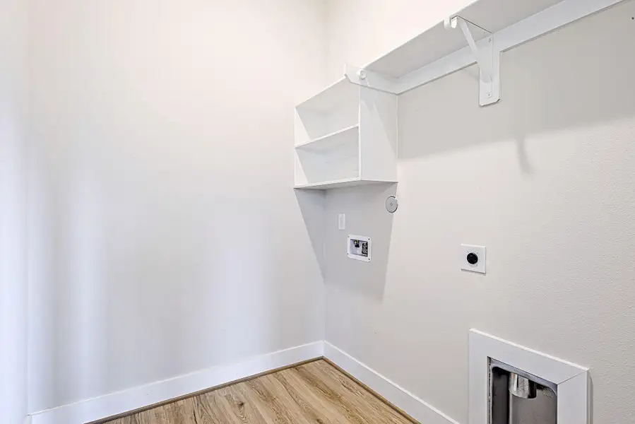 Tucked away for convenience, the laundry room is equipped with storage shelving and ready for full-size washer and dryer hookups. Tucked away for convenience, the laundry room is equipped with storage shelving and ready for full-size washer and dryer hookups.