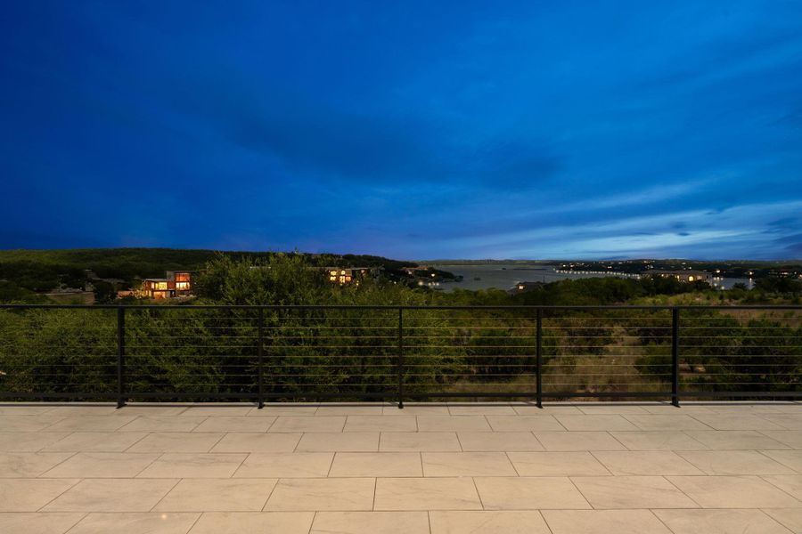 Perched above the landscape, this tiled patio offers an elevated panorama of the serene lake and distant city lights.