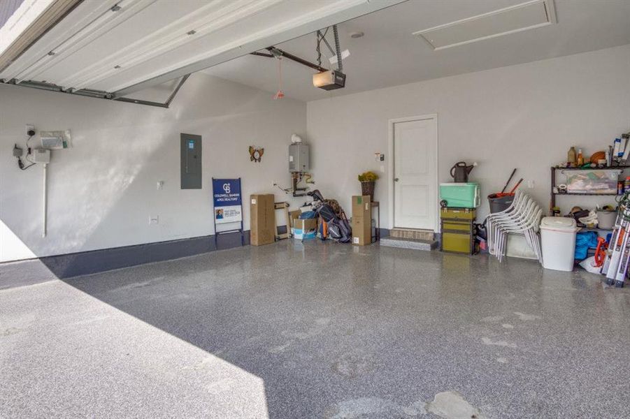 Garage featuring electric panel, a garage door opener, and water heater