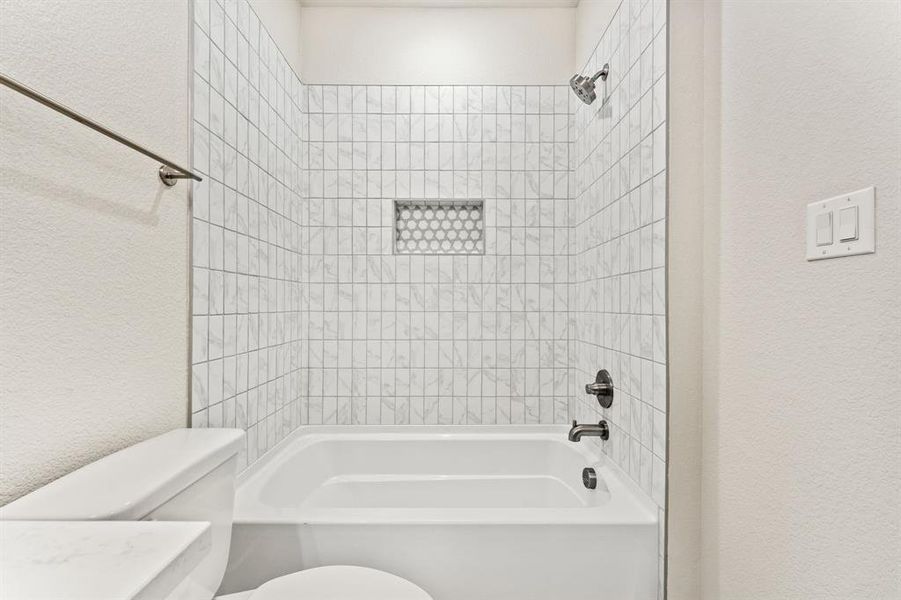 Bathroom with toilet and tiled shower / bath