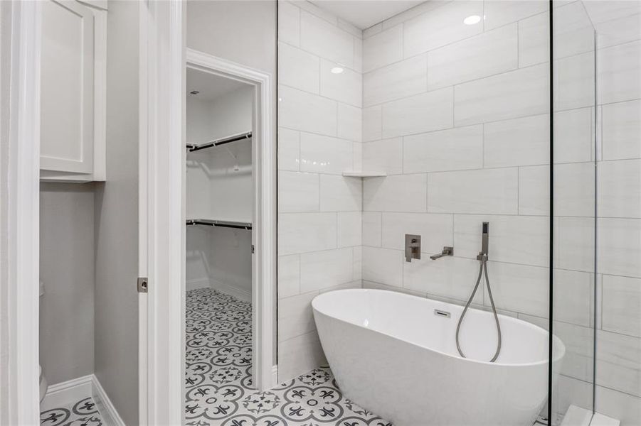 Bathroom featuring tile patterned flooring, tile walls, and a bath