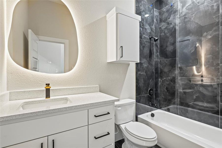 Bathroom featuring a textured wall, shower / washtub combination, and vanity