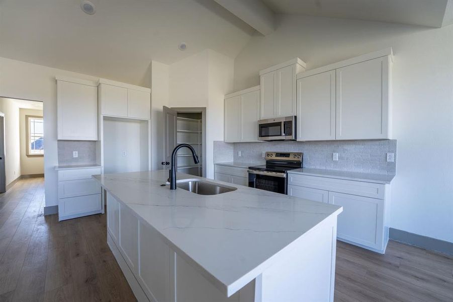 Kitchen featuring backsplash, white cabinets, appliances with stainless steel finishes, dark wood finished floors, and light stone counters Kitchen featuring backsplash, white cabinets, appliances with stainless steel finishes, dark wood finished floors, and light stone counters