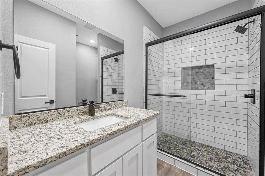 Bathroom featuring walk in shower, vanity, and hardwood / wood-style flooring