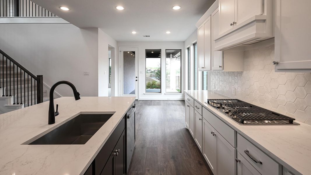 Kitchen with recessed lighting, light stone countertops, dark wood-style flooring, dark cabinetry, and appliances with stainless steel finishes