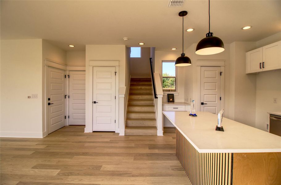 Kitchen with white cabinets, recessed lighting, pendant lighting, light wood finished floors, and a kitchen island