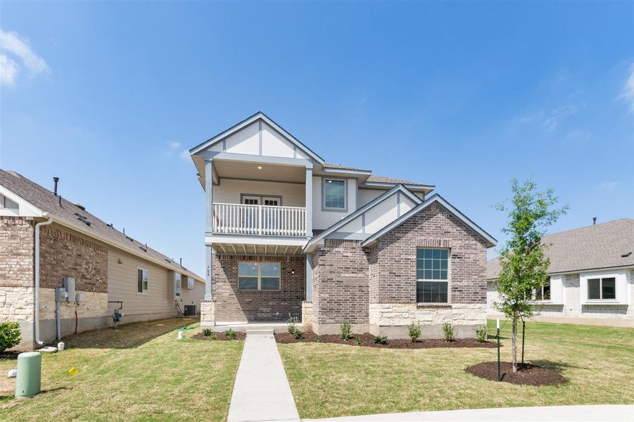 View of front of house with a balcony, brick siding, and a front lawn