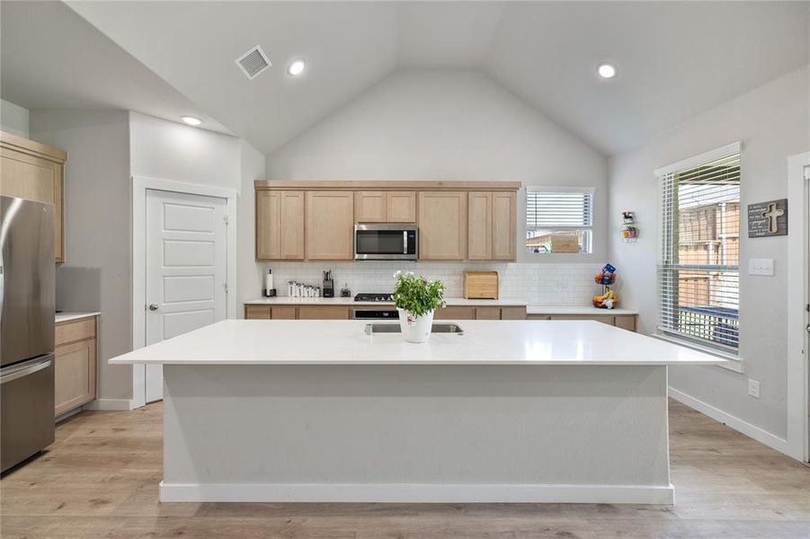 Kitchen with decorative backsplash, a center island, and appliances with stainless steel finishes