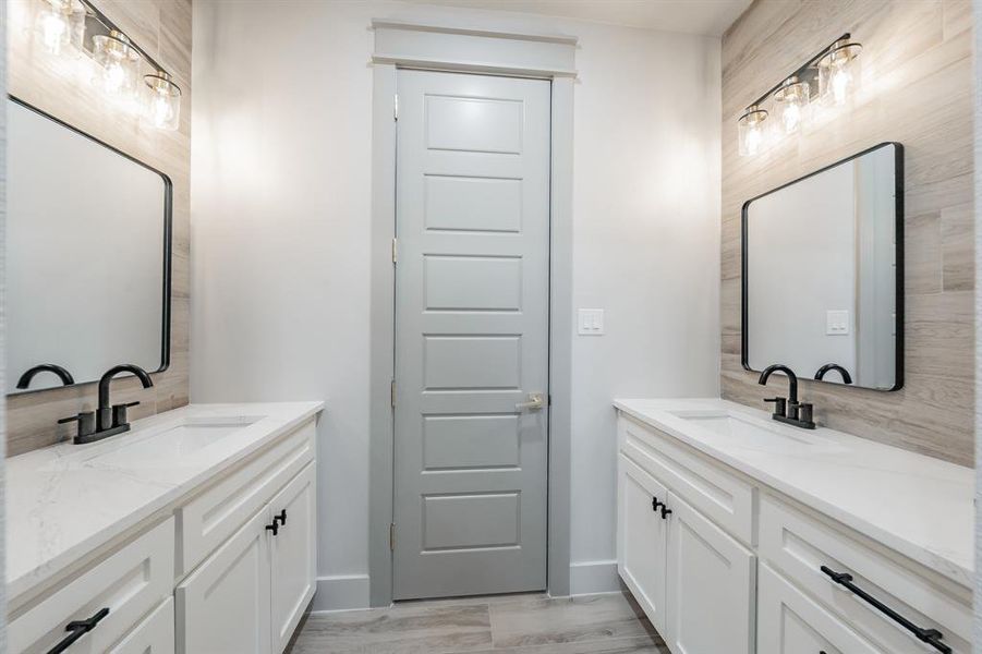 Full bath featuring two vanities, light wood-type flooring, and decorative backsplash