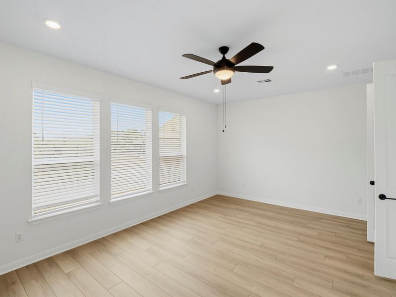 A naturally illuminated room features light wood flooring, several windows, and a ceiling fan for comfort. A naturally illuminated room features light wood flooring, several windows, and a ceiling fan for comfort.
