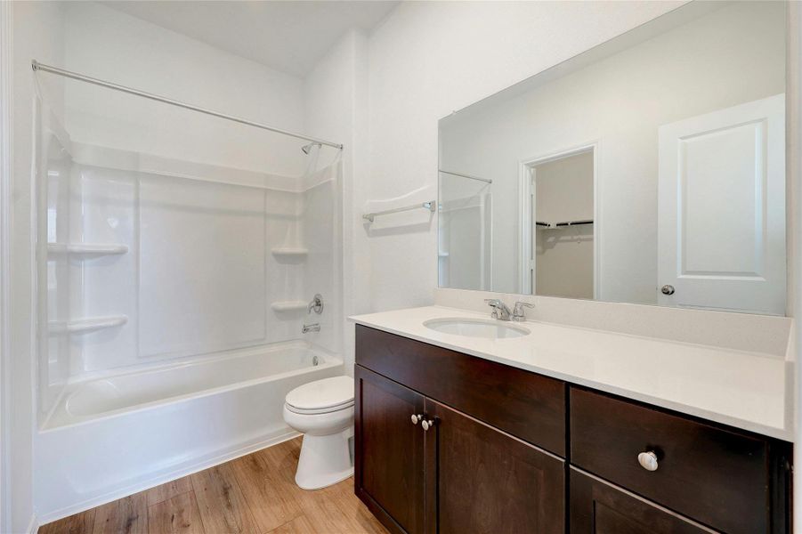 Bathroom featuring vanity, light wood-style flooring, bathing tub / shower combination, and a spacious closet
