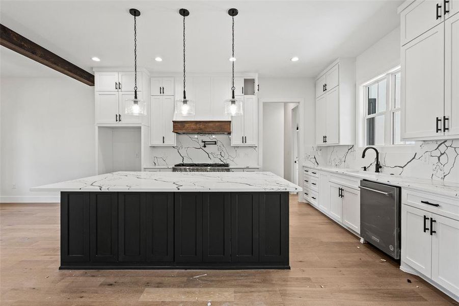 Kitchen featuring light stone counters, white cabinets, a spacious island, recessed lighting, and beamed ceiling Kitchen featuring light stone counters, white cabinets, a spacious island, recessed lighting, and beamed ceiling