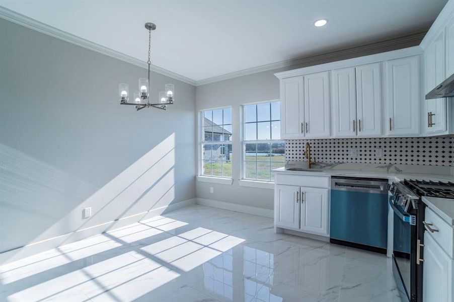 Kitchen with light marble finish flooring, dishwasher, white cabinets, black gas range oven, and crown molding