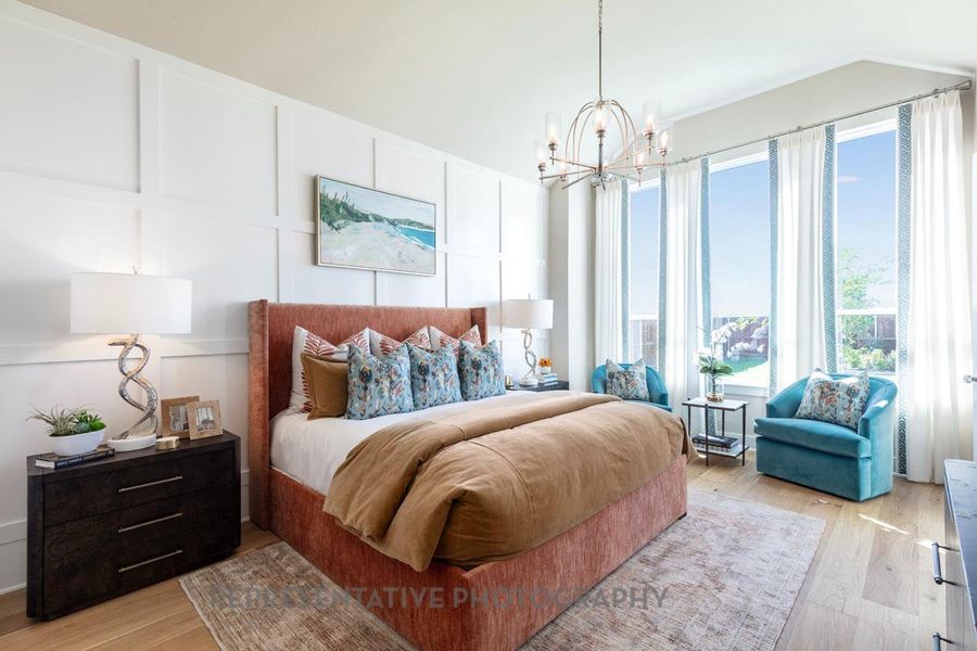 Bedroom with a decorative wall, light wood-style floors, and a chandelier