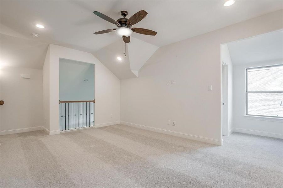 Additional living space with light carpet, lofted ceiling, and ceiling fan