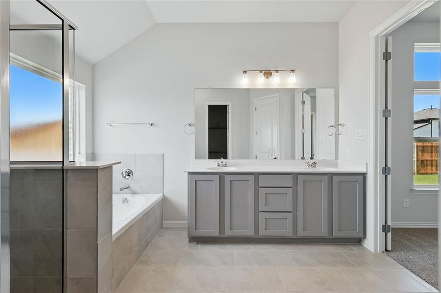 Bathroom featuring double vanity, a garden tub, lofted ceiling, healthy amount of natural light, and tile patterned flooring Bathroom featuring double vanity, a garden tub, lofted ceiling, healthy amount of natural light, and tile patterned flooring