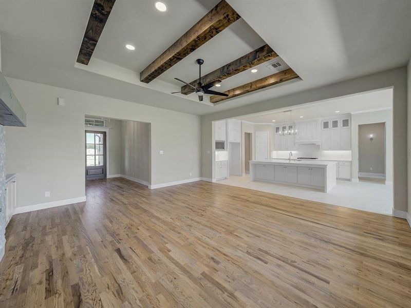 Unfurnished living room with recessed lighting, beam ceiling, a ceiling fan, light wood-type flooring, and a fireplace Unfurnished living room with recessed lighting, beam ceiling, a ceiling fan, light wood-type flooring, and a fireplace