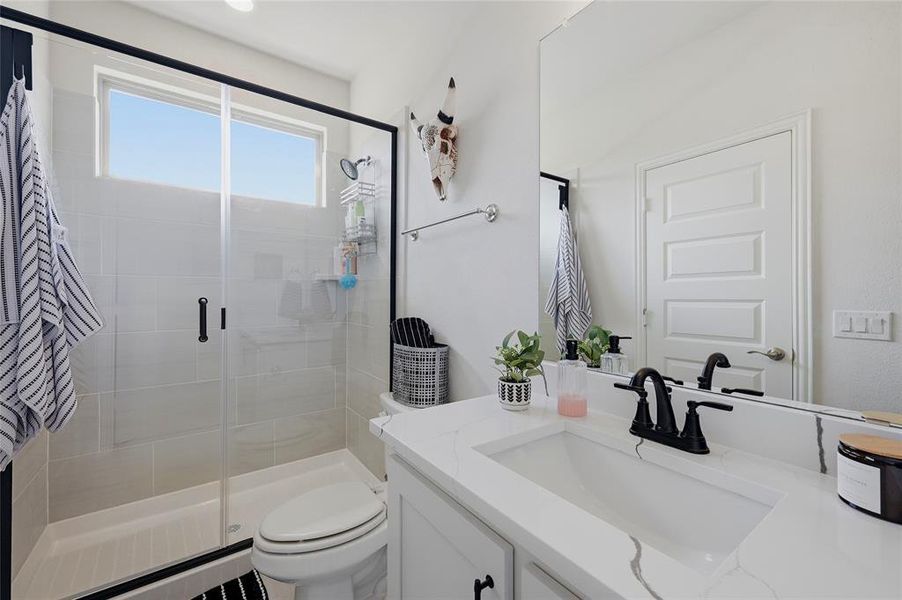 Contemporary bathroom featuring a walk-in shower with clear glass enclosure and matte black trim, a transom window, a single vanity with an undermount sink and stone-finish countertop, and a large mirror
