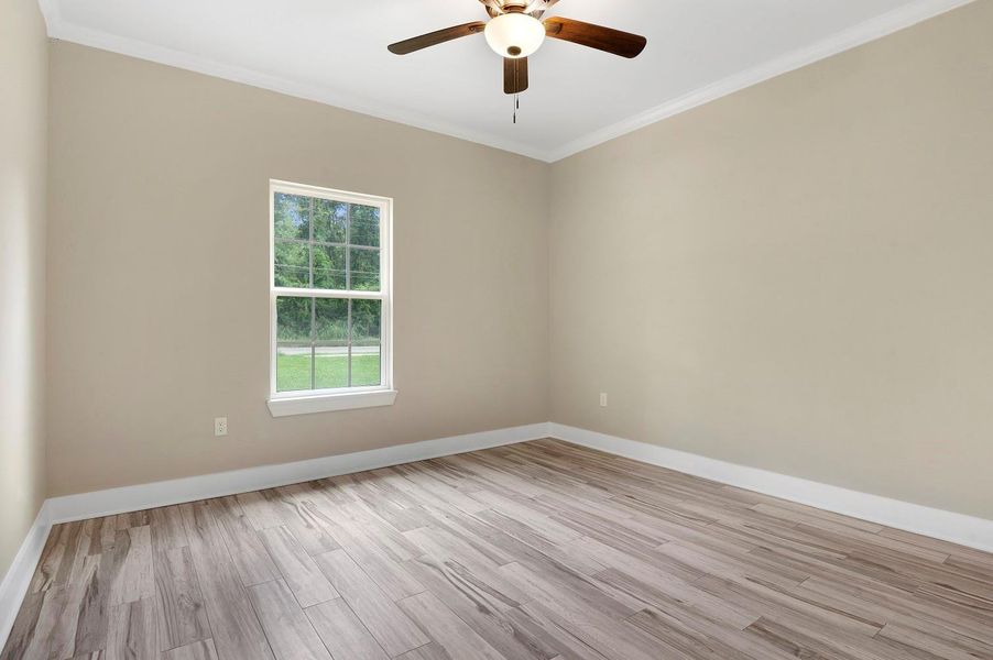 This room features neutral-toned walls, wood-look flooring, and a ceiling fan. A large window allows natural light to illuminate the space, creating a bright and airy atmosphere. Perfect for a bedroom or home office. This room features neutral-toned walls, wood-look flooring, and a ceiling fan. A large window allows natural light to illuminate the space, creating a bright and airy atmosphere. Perfect for a bedroom or home office.