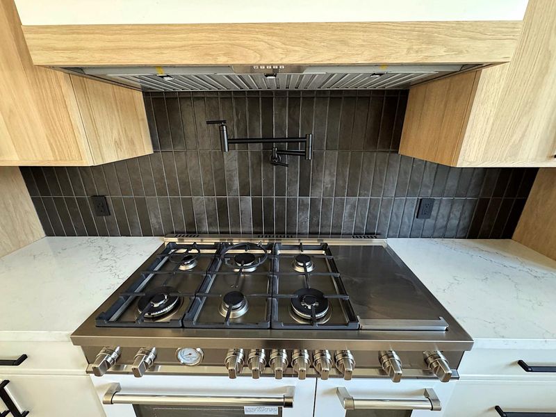 Interior details with light stone countertops, range, and backsplash