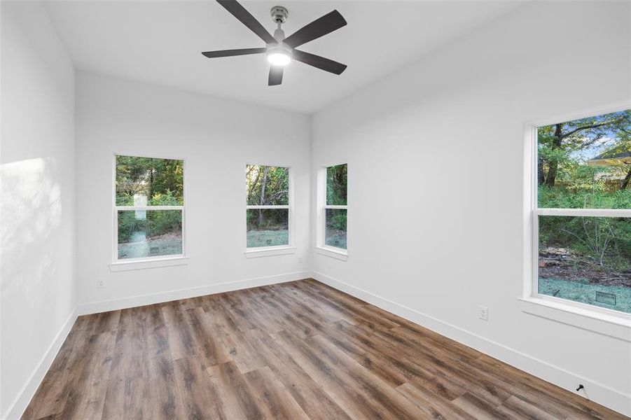 Spare room featuring hardwood / wood-style floors, ceiling fan, and a healthy amount of sunlight