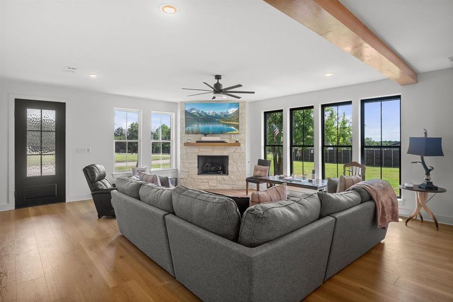 Living area featuring a stone fireplace, ceiling fan, wood finished floors, recessed lighting, and baseboards Living area featuring a stone fireplace, ceiling fan, wood finished floors, recessed lighting, and baseboards
