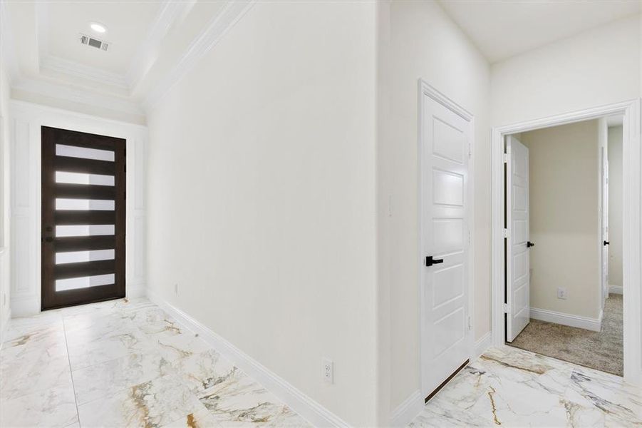 Foyer featuring ornamental molding, marble finish floor, visible vents, and baseboards Foyer featuring ornamental molding, marble finish floor, visible vents, and baseboards