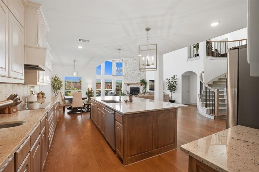 Kitchen with light stone counters, light wood-style floors, stainless steel appliances, hanging light fixtures, and recessed lighting Kitchen with light stone counters, light wood-style floors, stainless steel appliances, hanging light fixtures, and recessed lighting