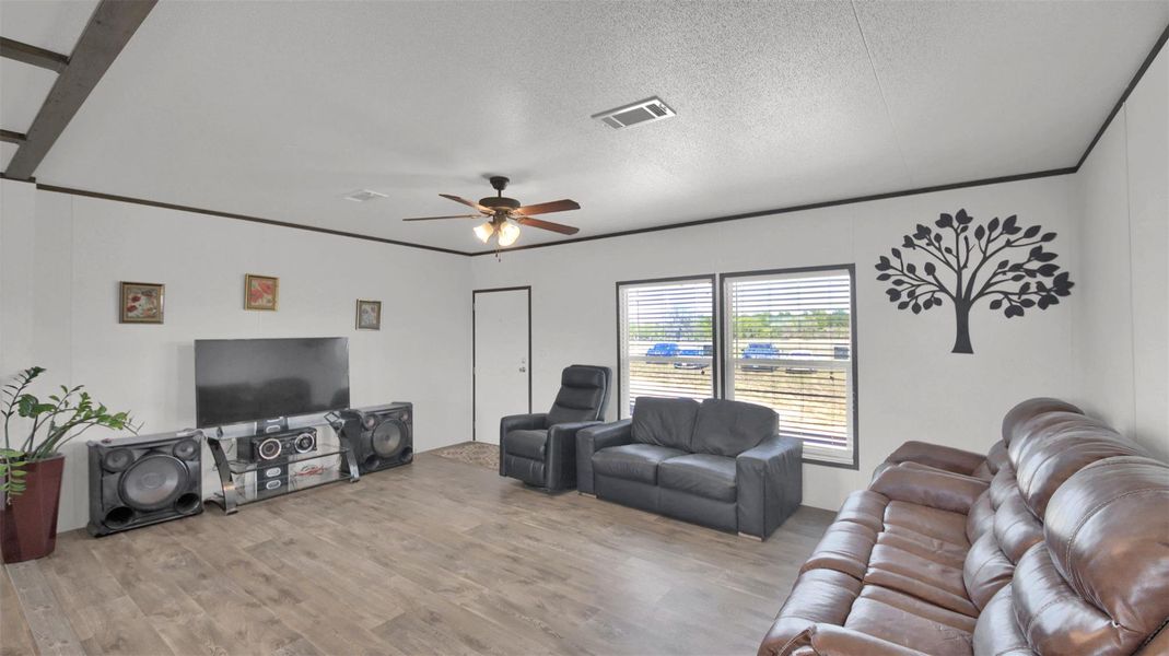 Living room with wood finished floors, ceiling fan, and a textured ceiling