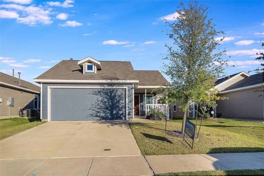 View of front of house with a shingled roof, a front lawn, driveway, and a garage