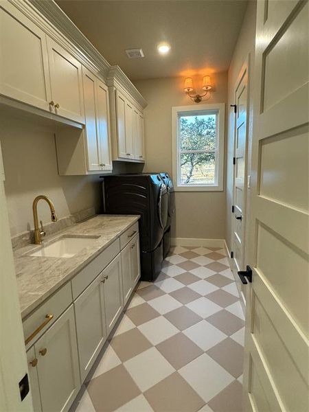 Clothes washing area featuring independent washer and dryer, cabinets, and sink