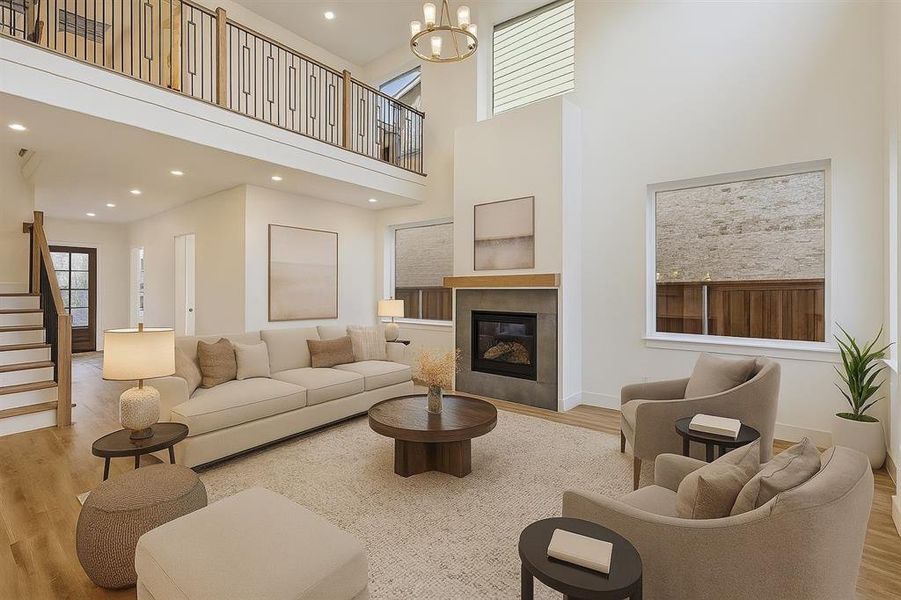 Living area with wood finished floors, a high ceiling, a tiled fireplace, recessed lighting, and stairway, virtually staged.