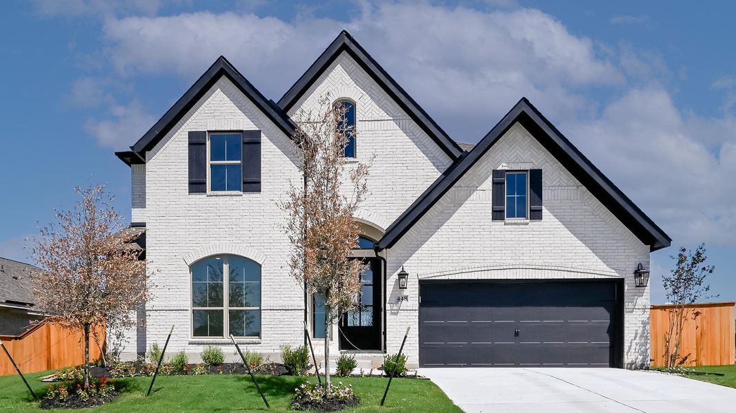 View of front of house with brick siding, a garage, and driveway