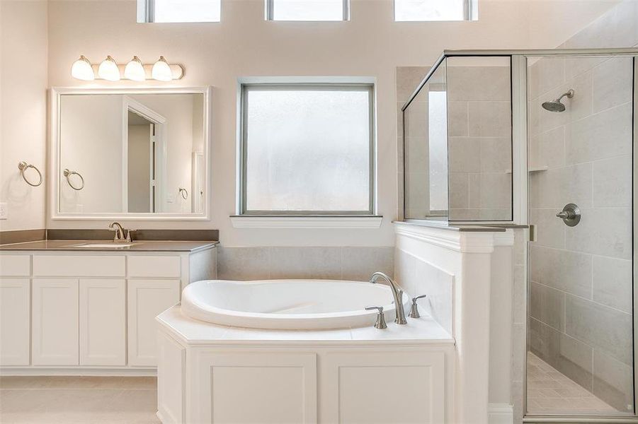 Bathroom featuring vanity, shower with separate bathtub, and tile patterned flooring